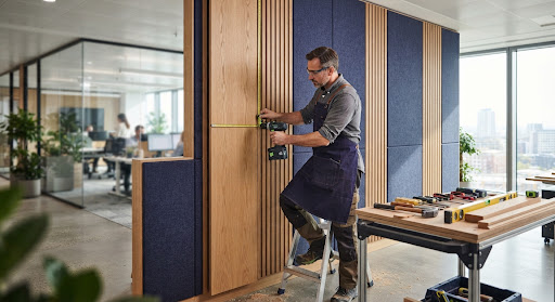Carpenter measuring and installing bespoke wood panelling